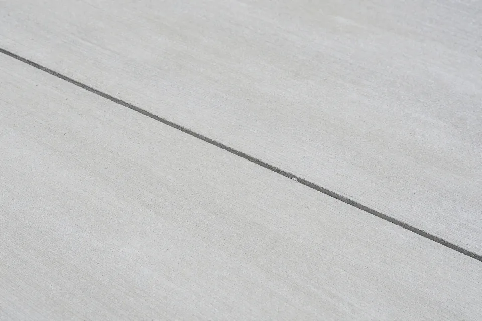 What most often causes small hairline cracks in a newly poured slab?
